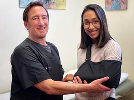 A photo of Dr. Weinman with a patient wearing a sling